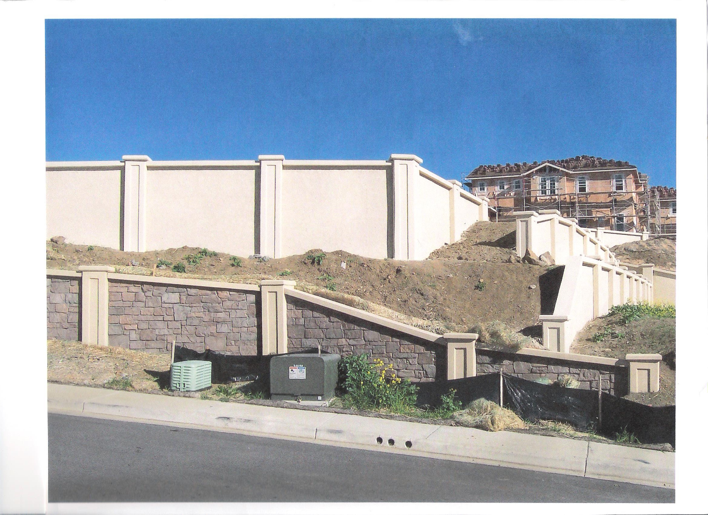 Multi-tiered precast concrete retaining wall on a California hillside with landscaping and modern home